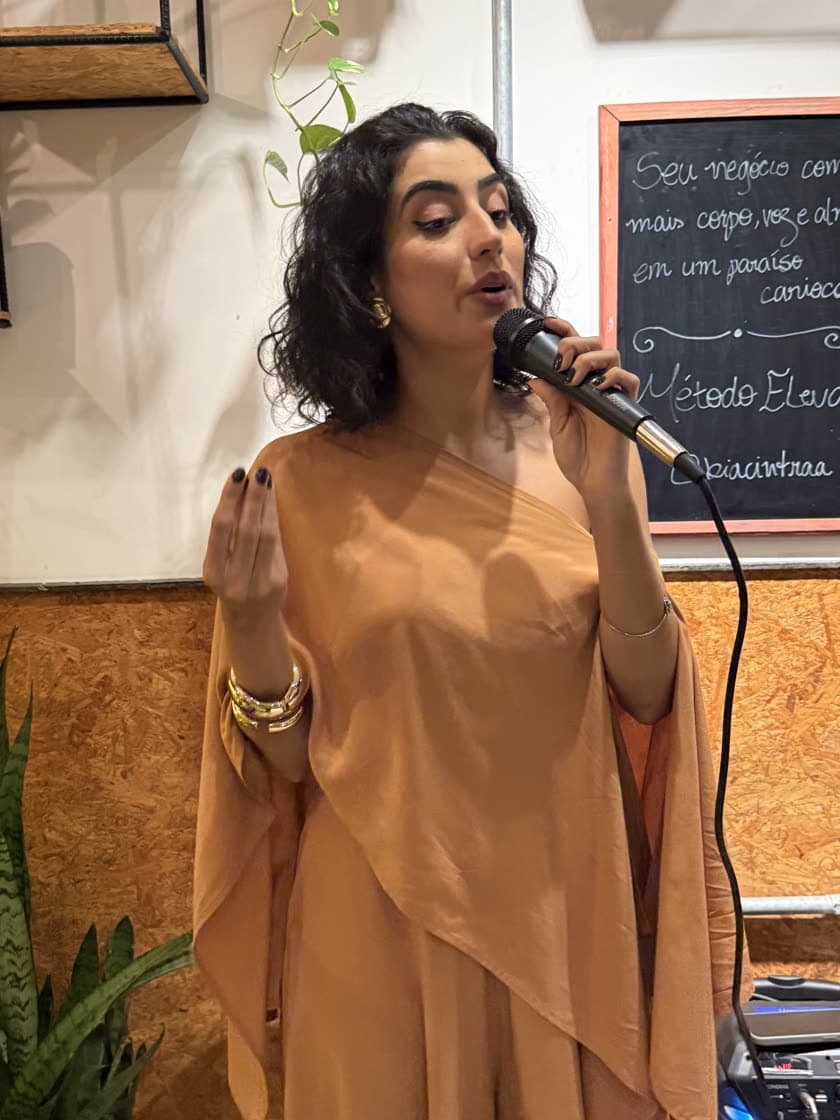 A Bia falando ao microfone, com o quadro do Método Eleva atrás